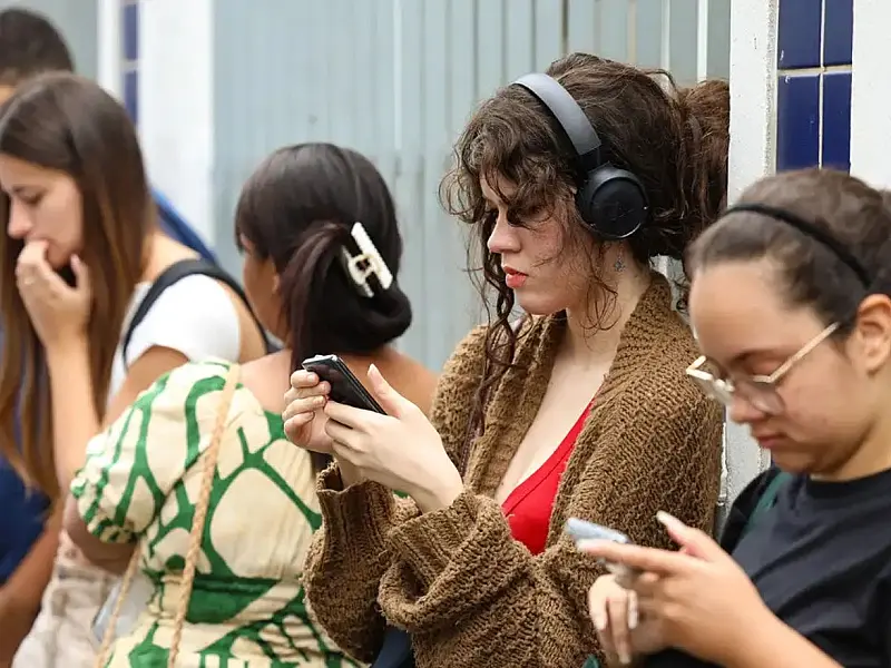 Estudantes utilizando o celular enquanto aguardam informações do Enem.