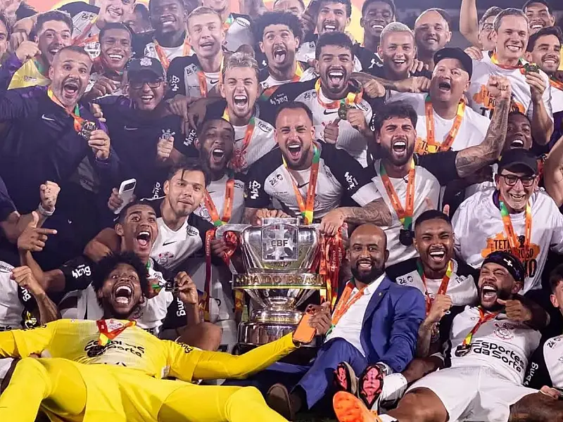 Jogadores do Corinthians comemoram o título da Copa do Brasil com troféu em campo.