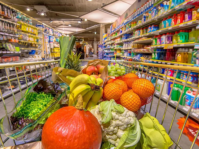 Corredor de supermercado com prateleiras de produtos e carrinhos de compras.