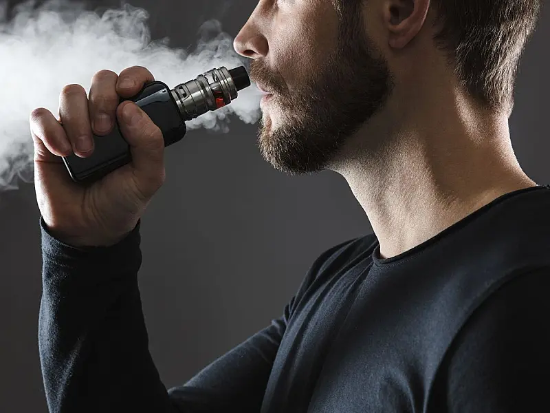 Pessoa utilizando cigarro eletrônico em meio a alerta da Anvisa sobre a proibição do vape no Brasil.