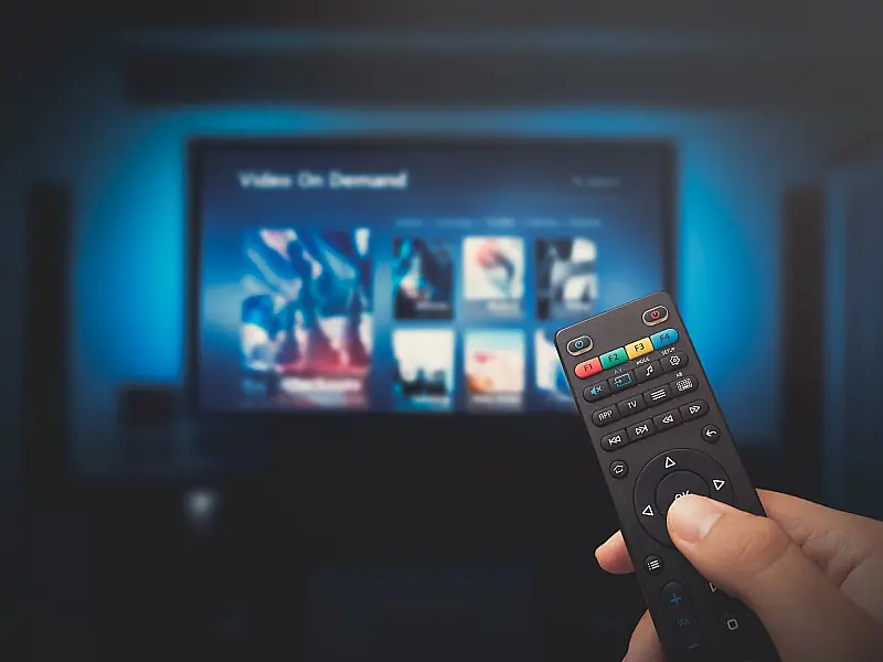 Controle remoto apontado para televisão exibindo plataformas de streaming