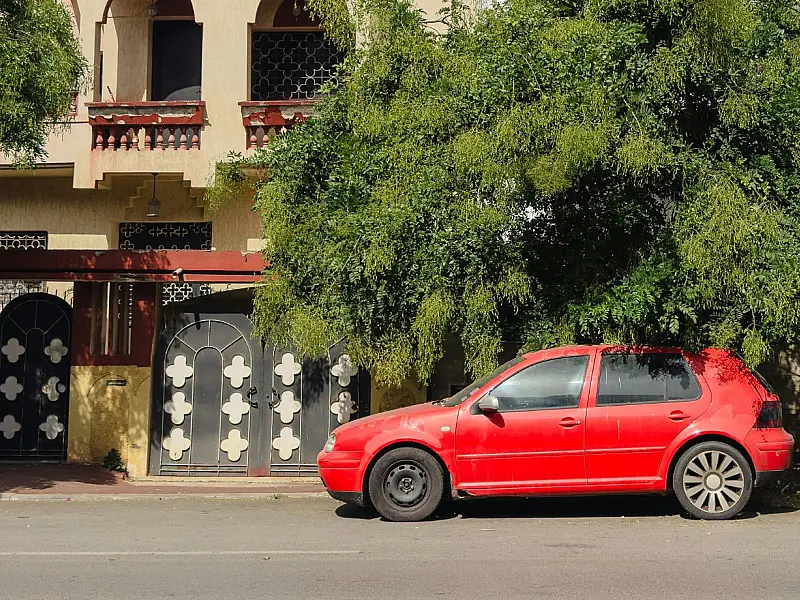 Veículo estacionado em frente a portão residencial, situação comum em bairros urbanos.
