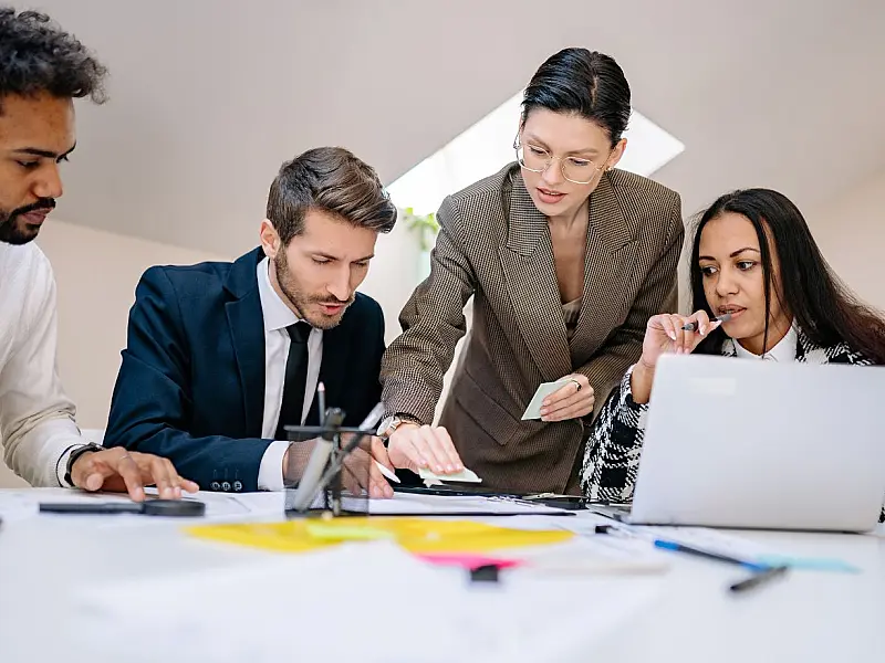 Pessoas conversando em reunião enquanto uma delas permanece em silêncio refletindo.