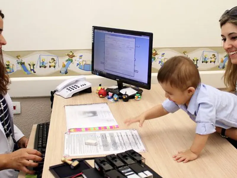 Profissional de saúde orienta mãe durante atendimento sobre cuidados com o desenvolvimento infantil.