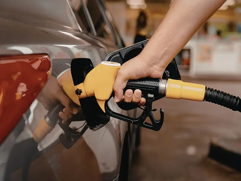 Pessoa abastecendo veículo em posto de combustíveis durante aumento dos preços da gasolina.