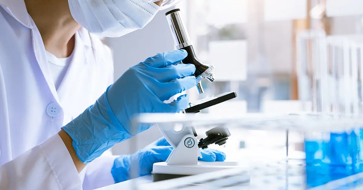 Cientista de pesquisa médica analisando amostras biológicas através de um microscópio em um laboratório moderno
