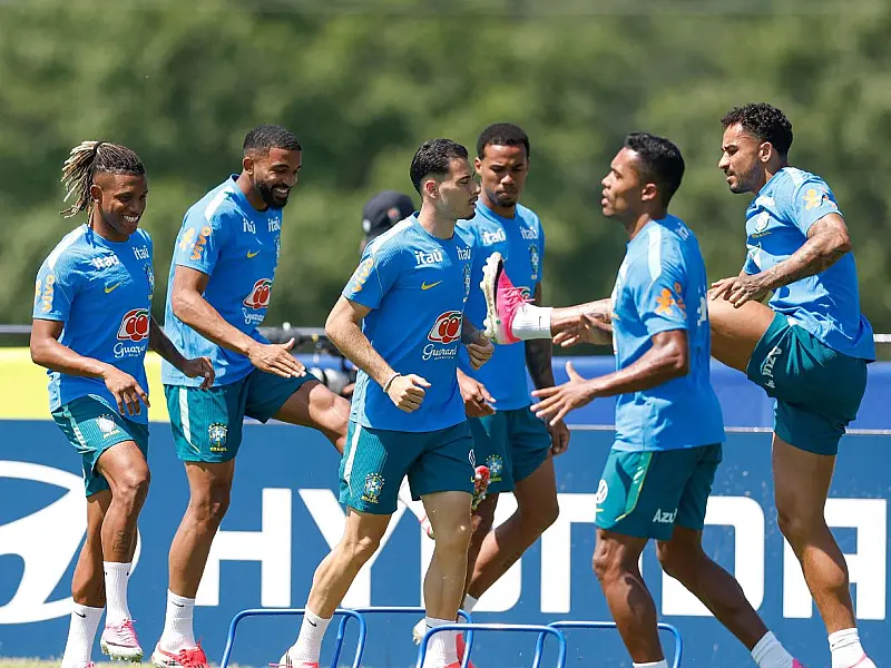 Jogadores da Seleção Brasileira, incluindo Danilo Santos, Bremer e Martinelli, correm juntos pelo gramado durante o aquecimento de um treino oficial