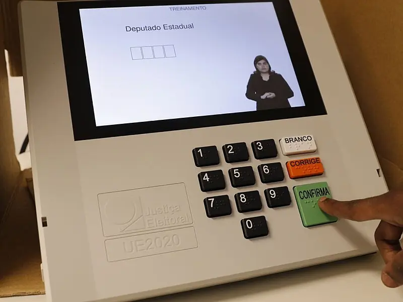 Detalhe em close do teclado de uma urna eletrônica da Justiça Eleitoral brasileira com o botão verde de confirmação em evidência