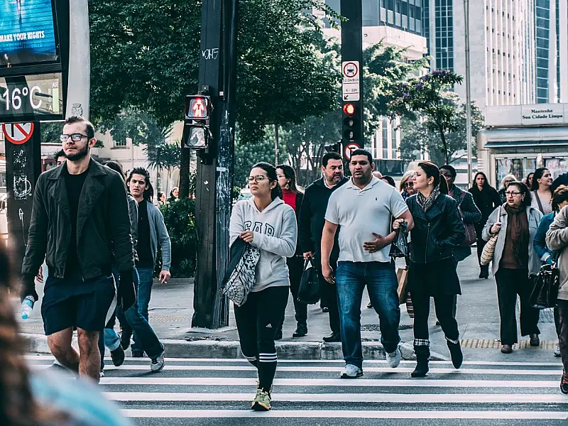 Vista de pessoas caminhando em uma faixa de pedestres em ambiente urbano durante o dia, representando a circulação dos entrevistadores nas cidades