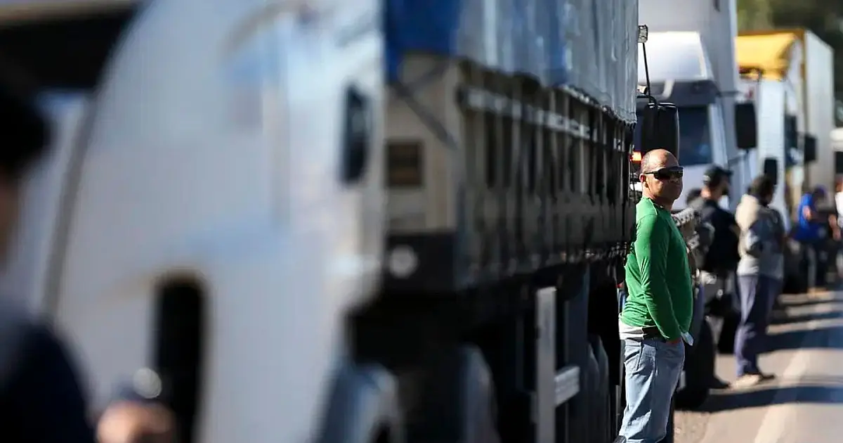 Caminhões de grande porte trafegam em pista dupla de uma rodovia brasileira sob céu aberto