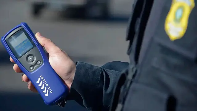Agente de trânsito utiliza equipamento durante operação de fiscalização da Lei Seca.