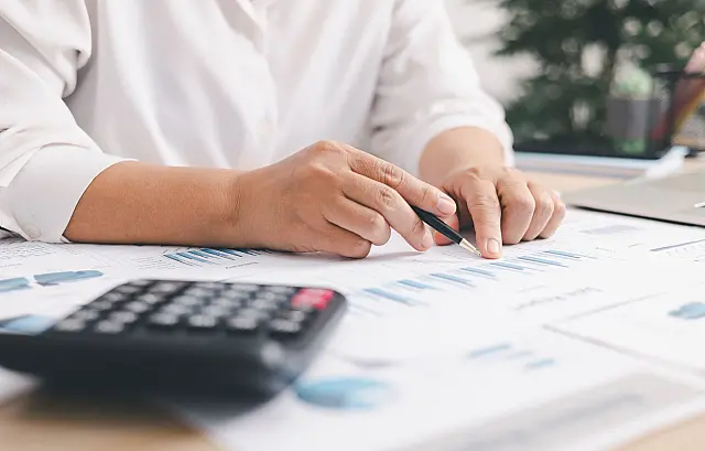 Profissional utilizando calculadora e notebook para análise de dados fiscais e planejamento orçamentário