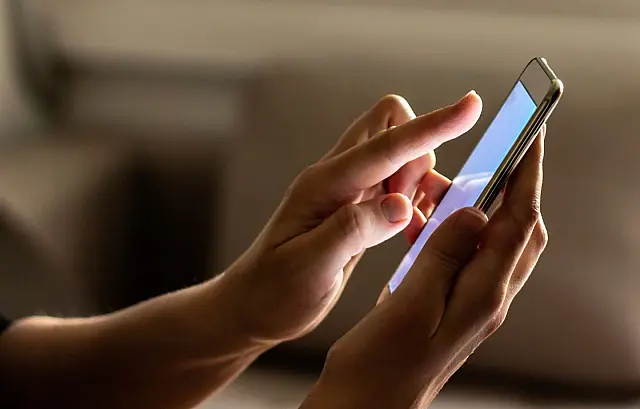 Mulher observando tela do aparelho celular ao receber ligação indesejada