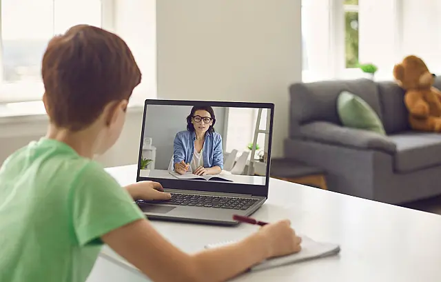 Pessoa sentada em uma mesa de estudos utilizando um notebook para estudar remotamente
