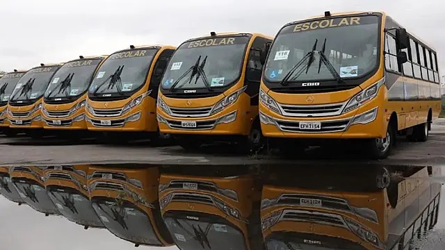 Ônibus amarelo de transporte escolar municipal estacionado em via pública em dia ensolarado