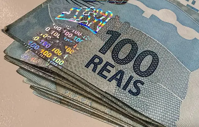 Várias notas de dinheiro da moeda real brasileiro empilhadas sobre uma superfície