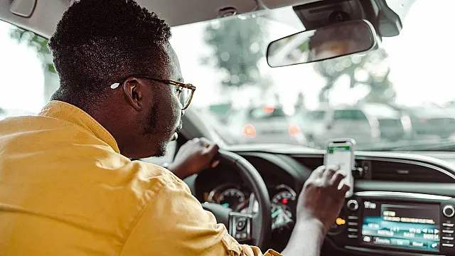 Motorista de aplicativo consulta o celular dentro do veículo