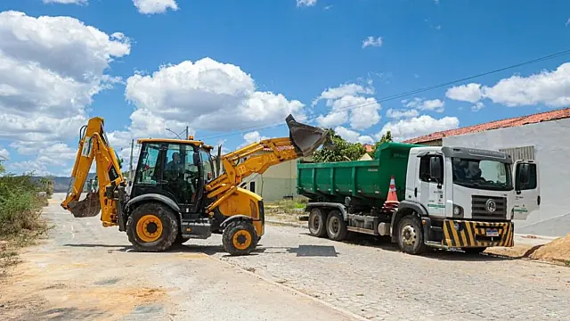 Retroescavadeira despeja resíduos em caçamba durante serviço de limpeza urbana em Caruaru.